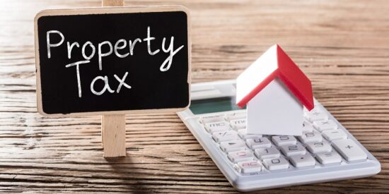 Property Tax Written On Blackboard With House Model On Calculator