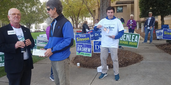 MAYOR WOODY WASHAM, FOREGROUND, AND ANDREW DUNCAN, BACKGROUND, HANDS OUT LITERATURE FOR HIS GRANDFATHER JIM DUKE