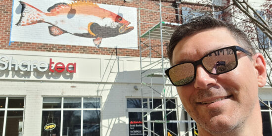 Justin Christenbery with his near finished 16-foot long grouper painting behind him